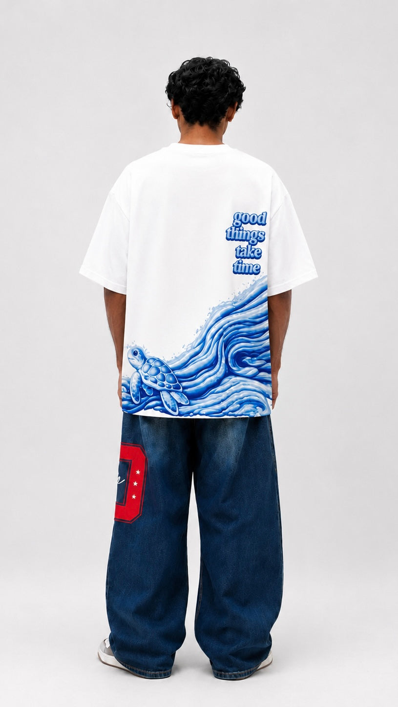 Person wearing a white t-shirt with a blue graphic design on the back, standing against a plain background.