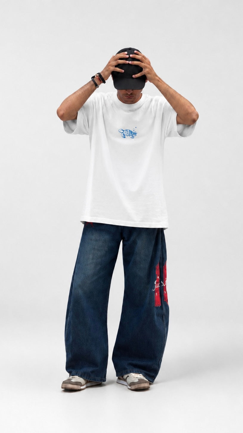 Person wearing a white t-shirt with a blue graphic design on the back, standing against a plain background.