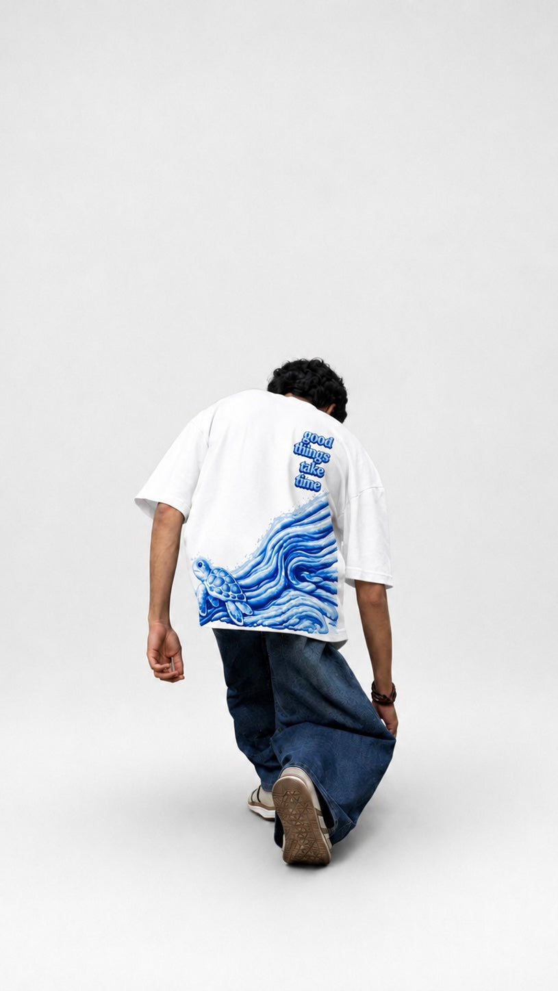 Person wearing a white t-shirt with a blue graphic design on the back, standing against a plain background.