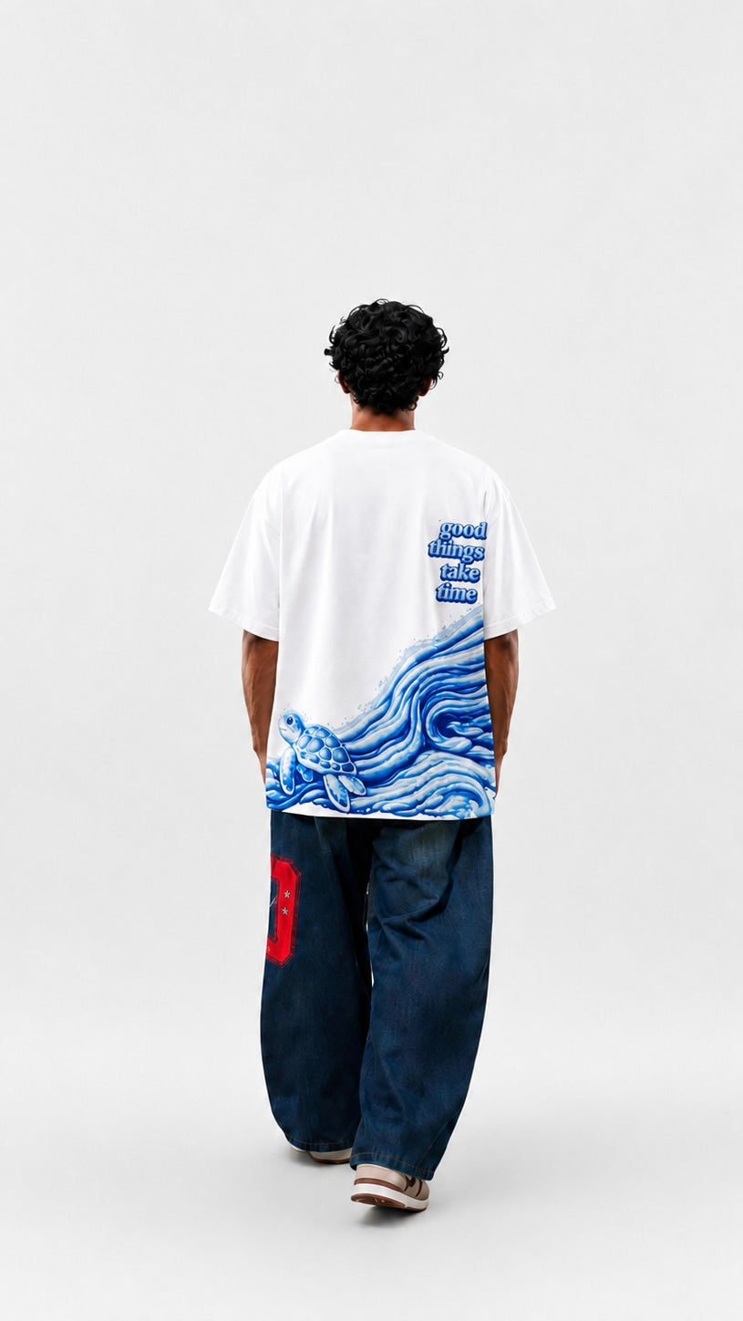 Person wearing a white t-shirt with a blue graphic design on the back, standing against a plain background.